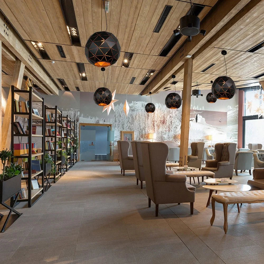 Подвесной светильник в виде черного металлического глобуса в интерьере современного помещения. Подходит для гостиной или столовой.